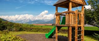 Klettergerüst mit grüner Rutsche mit Alpenpanorama