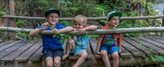 Walderlebnisplatz Kinder sitzen auf Holzbrücke