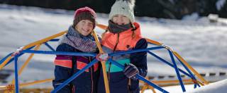 Kinder in Winterklamotten spielen im Schnee