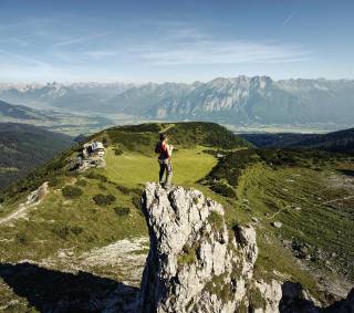 Frau beim Klettern auf Berggipfel mit Alpen im Hintergrund